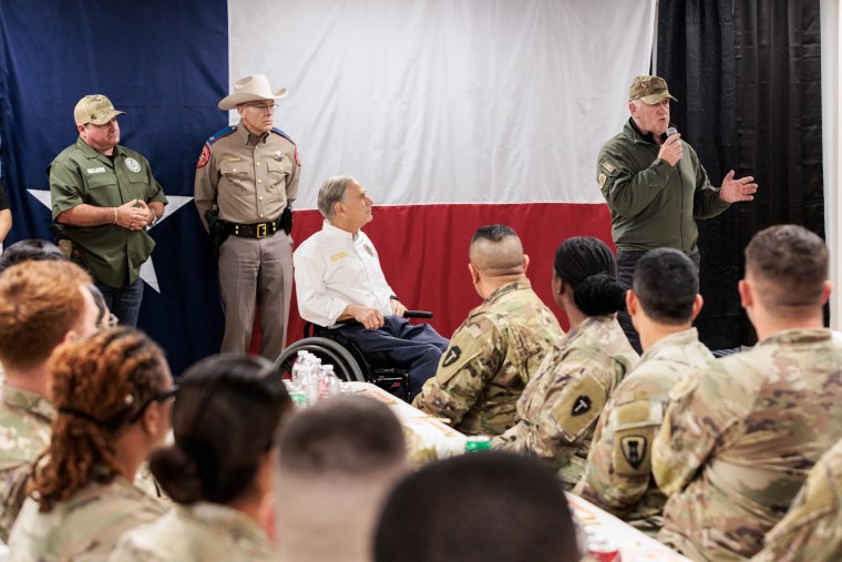 Tom Homan speaks to National Guard members, Greg Abbott is seated next to him in a wheelchair