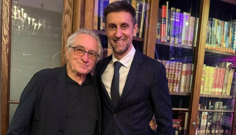 Actor Robert De Niro and SIC program director Daniel Oliveira side by side in front of a bookshelf.