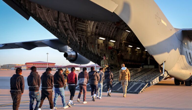 Illegal immigrants deported from the US, enter a military plane with handcuffed hands and feet, and chains around the waist.