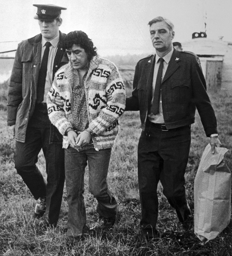 Law enforcement officers with a handcuffed Leonard Peltier