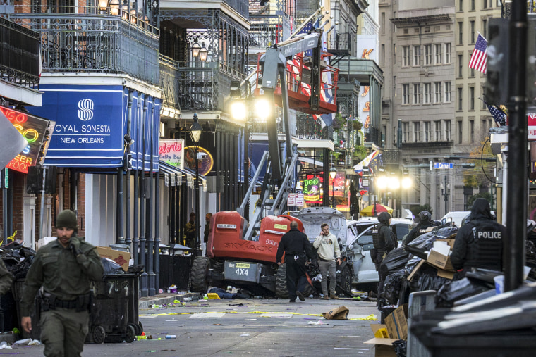 Image: Police investigators surround a white truck that has been crashed into a work lift