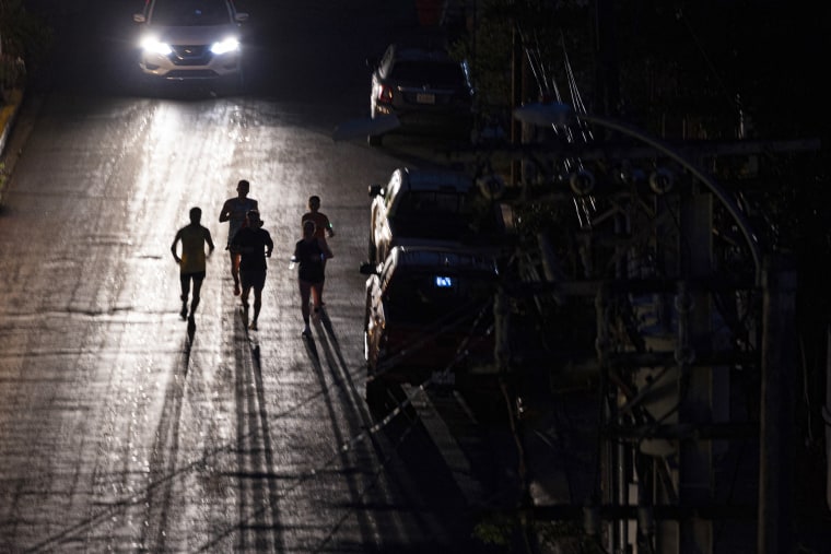 Joggers run on a dark street in San Juan, Puerto Rico, during major power on Dec. 31, 2024.