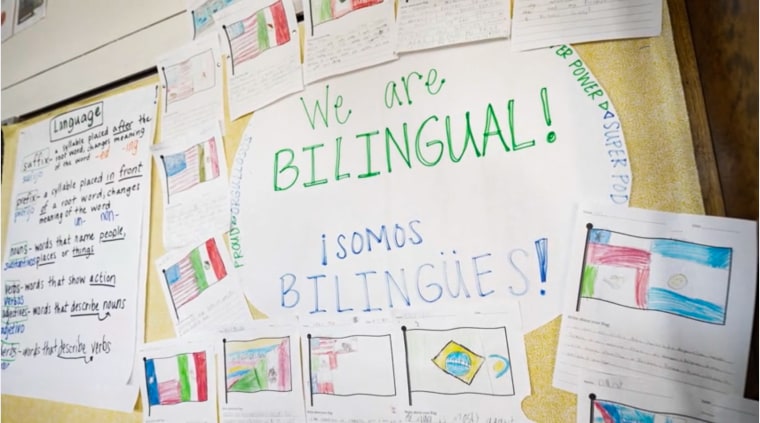 A sign says "We are bilingual! Somos bilingues!" on a classroom board