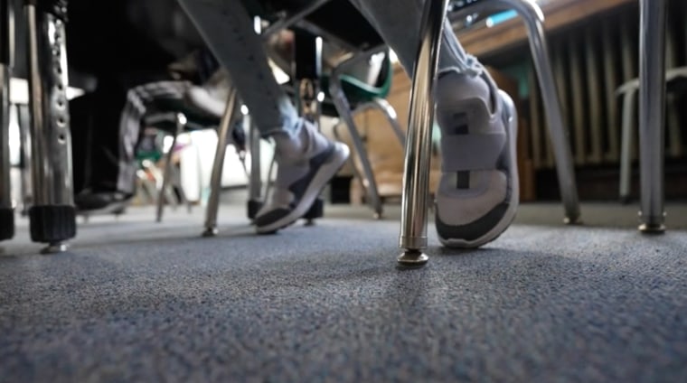 Feet are seen underneath school desks