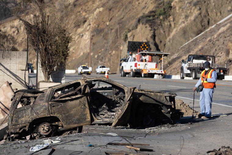 A worker checks for gas leaks in a burned car