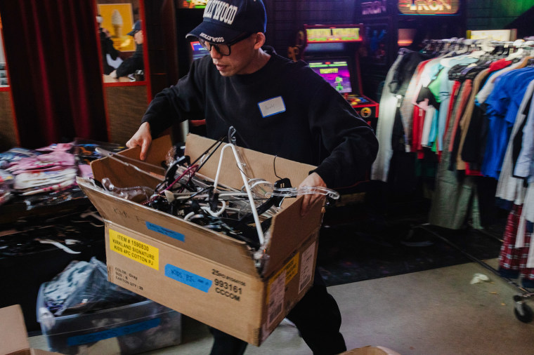 A volunteer hauls clothing hangers in a box.