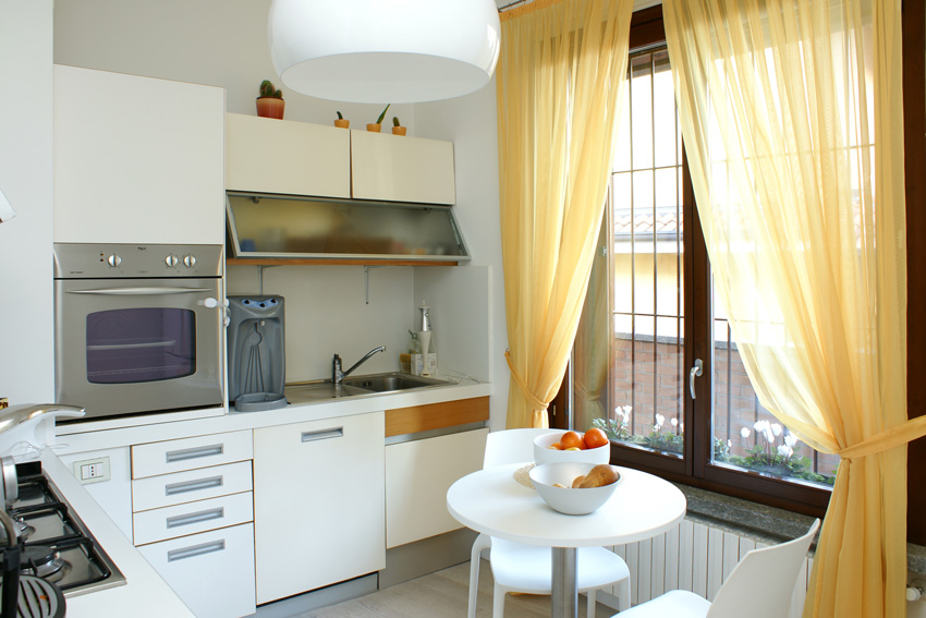 Transparent yellow curtains in a small modern white cuisine.