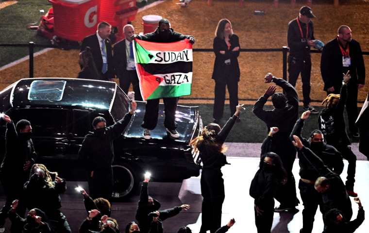 A protestor holds a Palestinian flag with the words "Gaza" and "Sudan" as US rapper Kendrick Lamar performs during Apple Music Halftime Show.