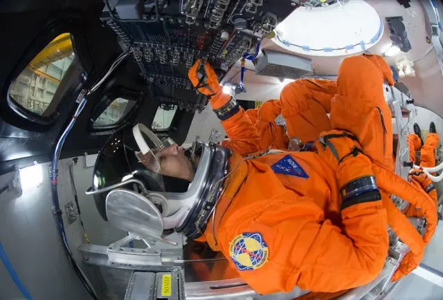 Specializing in space costumes demonstrate how the four crew would be positioned for launch within the Orion spacecraft.