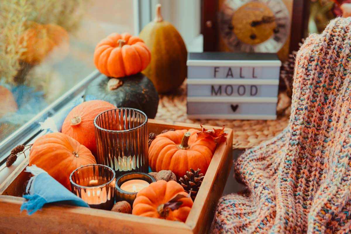 autumn centerpiece with pumpkins and glass jars in a wooden box