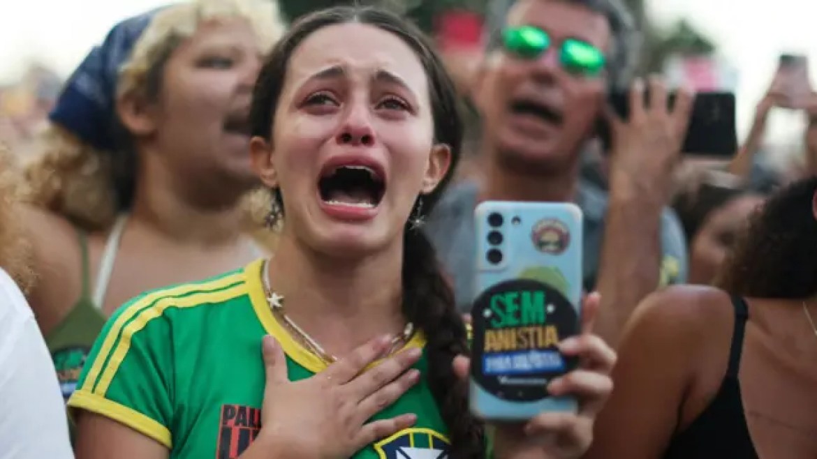 Woman dressed in the selection shirt cries while holding a cell phone with a "no amnesty" sticker.