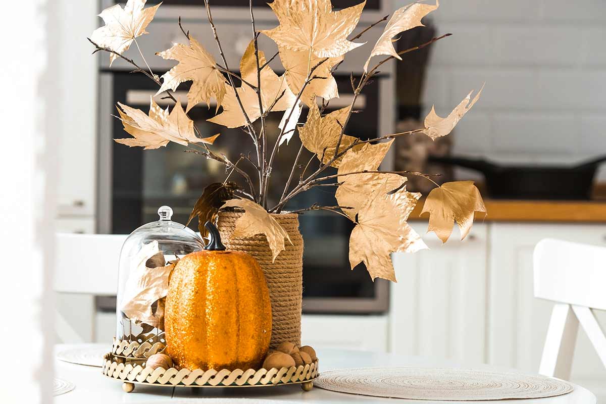 centerpiece with pumpkin with glitter and vase with dry leaves