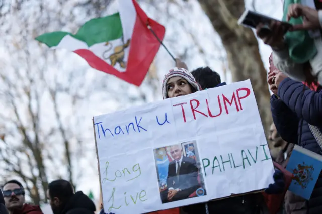 Woman holds a sign with a photo of Pahlavi that says: Thank you Trump, long live Pahlavi'