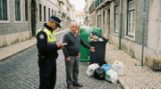 Polícia a multar cidadão por este ter deixado lixo fora do contentor. Crédito: Gemini