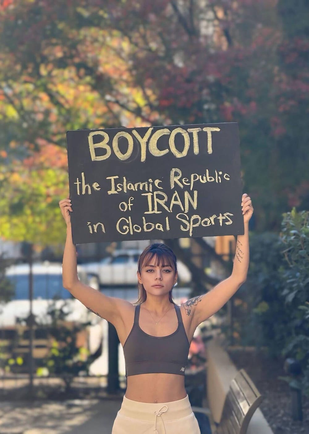 Shiva Amini, who defected from Iran after being caught playing football without her hijab in public, displays a sign protesting the Iranian regime (Shiva Amini via CNN Newsource)