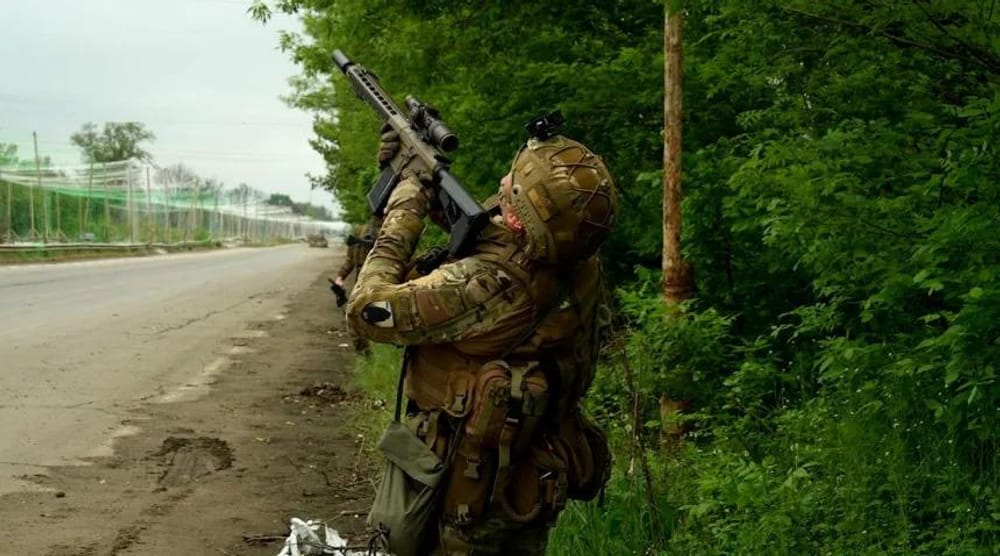 A Ukrainian soldier points to a Russian drone in the sky above the "Road of Life" (CNN)