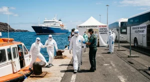 Passengers wearing full protective gear disembark from a small boat at Tenerife port from the MV Hondius.