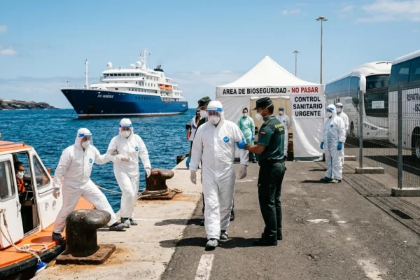 Passengers wearing full protective gear disembark from a small boat at Tenerife port from the MV Hondius.